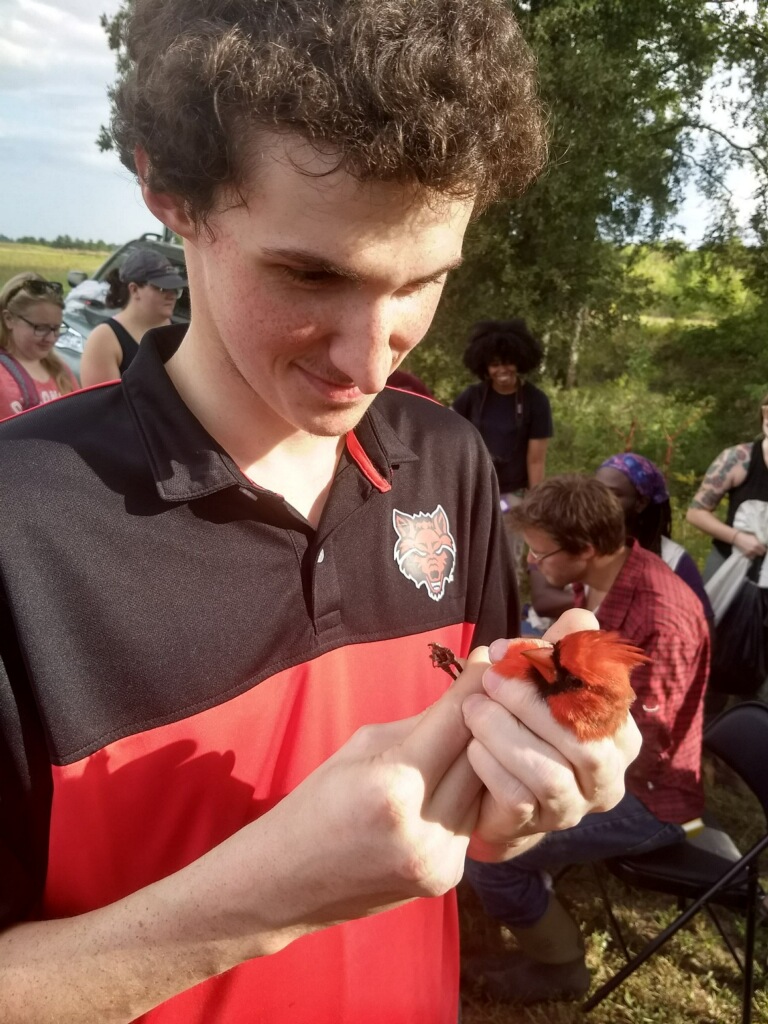 Biology student Gregory Daniels holding a cardinal 